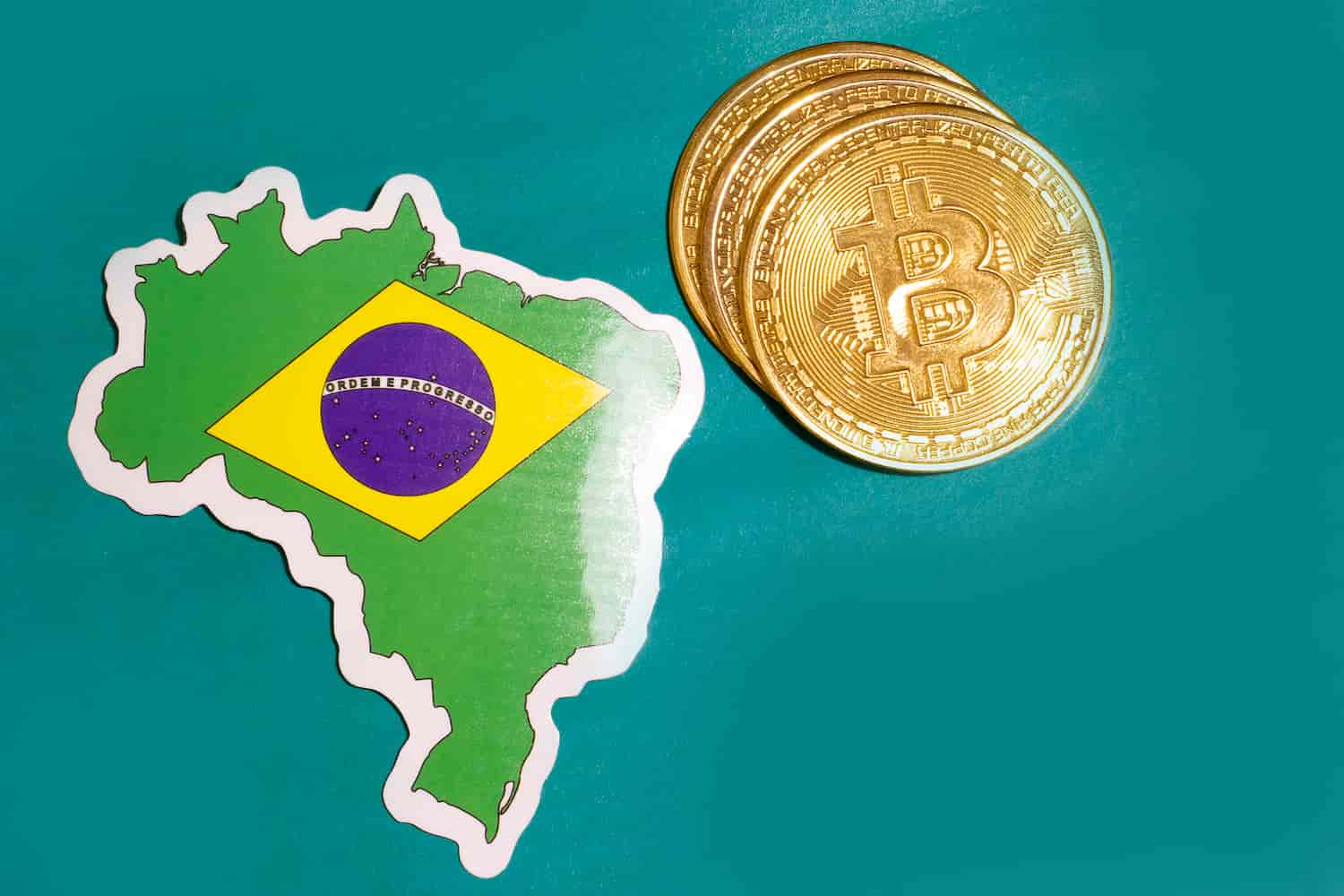 Moedas de bitcoin ao lado de mapa do Brasil